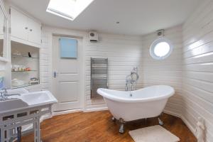 een witte badkamer met een bad en een wastafel bij Boathouse Bliss in Heacham