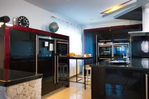 une cuisine avec des armoires noires et une horloge murale dans l'établissement Modern Station Apartment Mhlin, à Möhlin