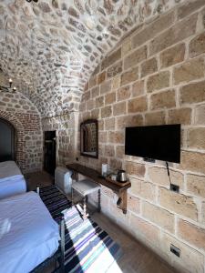 una camera da letto con un muro di mattoni e una TV di Arami Han Konağı a Mardin