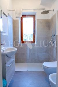 een badkamer met een wastafel en een toilet en een raam bij Carla 1 in Campese +11 foto's