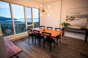 een eetkamer met een tafel, stoelen en ramen bij Luxury Coffee Bean Condo - Pool & Stunning View in Baie-Saint-Paul