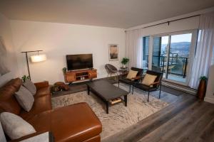 een woonkamer met een bank, stoelen en een televisie bij Luxury Coffee Bean Condo - Pool & Stunning View in Baie-Saint-Paul