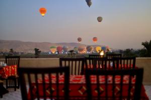 a table with chairs and hot air balloons in the sky at Saray El Omda - Wellness & Retreat Village in Luxor