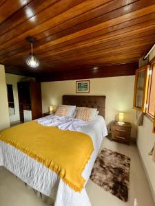 a bedroom with a large bed with a yellow blanket at Casa Moreira´s Chalés in Monte Verde