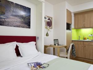a hotel room with a bed and a kitchen at Aparthotel Adagio Paris Vincennes in Vincennes