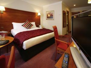a hotel room with a bed and a flat screen tv at Mercure York Fairfield Manor Hotel in York
