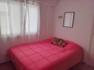 een roze bed in een kamer met een raam bij Departamento Falucho in Mar del Plata