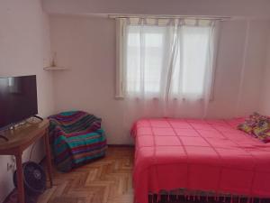 een slaapkamer met twee bedden, een tv en een raam bij Departamento Falucho in Mar del Plata +4 foto's