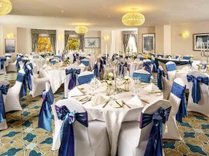 a banquet hall with white tables and blue bows at Mercure Chester Abbots Well Hotel in Chester +90 photos