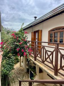 a balcony of a house with pink flowers on it at Casa Moreira´s Chalés in Monte Verde