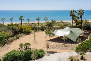 a tent on the beach with the ocean in the background at Sabàtic Gavà Mar, Barcelona, a Tribute Portfolio Hotel in Gavà
