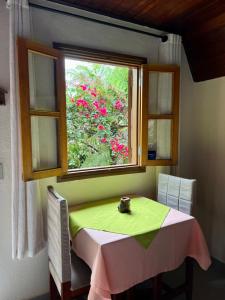 a table and a window with a table and chairs at Casa Moreira´s Chalés in Monte Verde