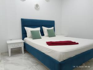 a blue and white bed with a red blanket on it at Résidence Debbabi in Monastir