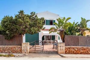 a white house with a fence and a table at Villa Jultomas in Cala en Bosc