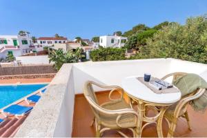 a table and chairs on a balcony with a pool at Villa Jultomas in Cala en Bosc
