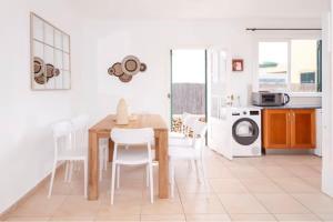 a kitchen with a wooden table and white chairs at Villa Jultomas in Cala en Bosc