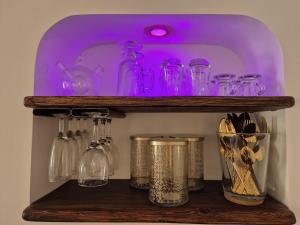 ein Regal mit vielen Glasgefäßen und einem violetten Licht in der Unterkunft Kama Muta in Callas