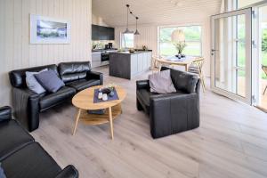 a living room with black leather furniture and a table at Lille Traehus in Dreschvitz