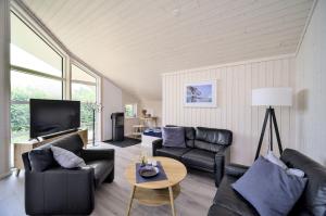 a living room with black leather furniture and a tv at Lille Traehus in Dreschvitz