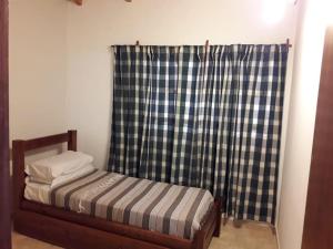 a small bed in a room with a plaid shower curtain at Departamento ALEM in Federación