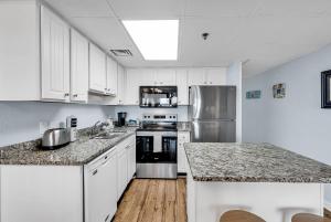 a kitchen with white cabinets and a stainless steel refrigerator at Oceanfront Luxury 2BR Litchfield Beach Escape in Pawleys Island