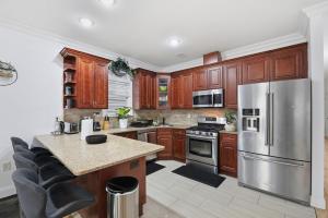 a kitchen with wooden cabinets and a stainless steel refrigerator at Sleeps 18! - 6 BR - 2 Kitchens in Jersey City