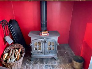 una stufa a legna in una camera rossa con cesto di Coombehayes Barn a Uplyme
