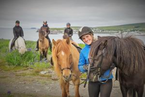 Una donna è in piedi accanto a un cavallo marrone di Saltvík Farm Guesthouse a Húsavík