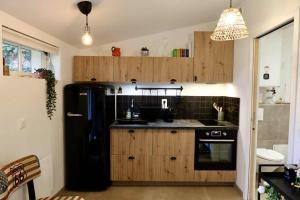 a kitchen with a black refrigerator and wooden cabinets at Le joli jardin face à l'Abbaye in Pont-à-Mousson