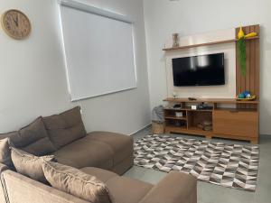 un salon avec un canapé et une télévision à écran plat dans l'établissement Casa Lago da Dinda 3, à Espirito Santo Do Pinhal 4 autres photos