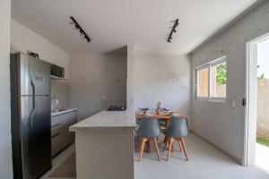 a kitchen with a refrigerator and a table with chairs at Apartamentos Curimã in Passo de Camarajibe