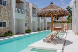 a swimming pool with two chairs and an umbrella at Apartamentos Curimã in Passo de Camarajibe