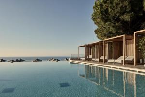 法里拉基Esperos Village Blue & Spa - Adults Only的一个带椅子的游泳池,背景是大海