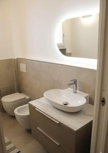 een badkamer met een wastafel, een toilet en een spiegel bij Appartamento in centro in Castelsardo