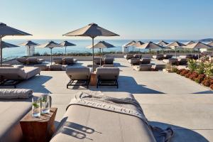a row of lounge chairs and umbrellas on a beach at Esperos Village Blue & Spa - Adults Only in Faliraki +57 photos