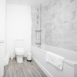 a white bathroom with a tub and a toilet at Modern Two Bed Apartment - Sleeps 3 - Parking - Netflix 50C in Netherton