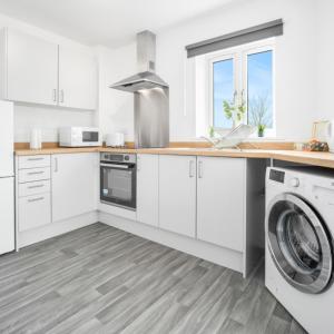 a kitchen with white cabinets and a washer and dryer at Modern Two Bed Apartment - Sleeps 3 - Parking - Netflix 50C in Netherton