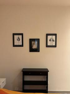 drei gerahmte Bilder an einer Wand mit einem Tisch in der Unterkunft villa Pieri appartamento black in Fauglia