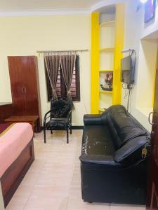 - un salon avec un canapé en cuir noir et une chaise dans l'établissement budget stay-mystique inn, à Ooty