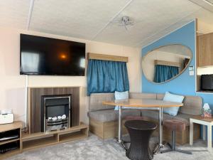 a caravan living room with a table and a tv at Coastal Beachfront Caravan in Brightlingsea