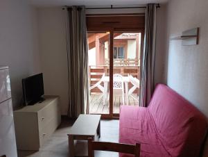 a living room with a pink couch and a television at Chalets de L Isard D N35 2P6 in Les Angles