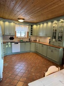 eine Küche mit grünen Schränken und einer Holzdecke in der Unterkunft Luxurious Log House - Gränsfors 354 in Bergsjö