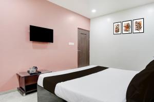 a bedroom with a bed and a flat screen tv at HOTEL O THE COZY INN in Sakardarā