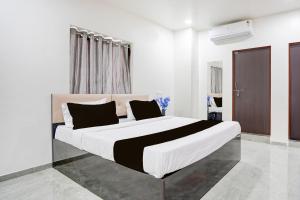 a white bedroom with a large bed with black pillows at HOTEL O THE COZY INN in Sakardarā