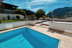 a swimming pool in front of a house with a mountain at Sonnhang Apartment Unterkofler in Sankt Johann im Pongau