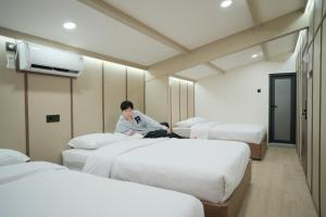 a woman sitting on a bed in a hotel room at INSAHAUS Guest House in Kotalama