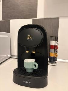una macchinetta del caffè con una tazza sopra di CosyLoft a Châlette-sur-Loing