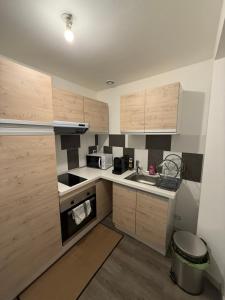 una piccola cucina con armadi in legno e lavandino di CosyLoft a Châlette-sur-Loing