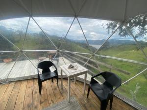 a room with two chairs and a table on a balcony at GLAMPiNG AMOR AMOR GUATAVITA in Guatavita
