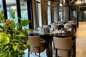 a dining room with tables and chairs and a plant at Luxe Chalet Leeuwenhart - recreation only in Hoenderloo
